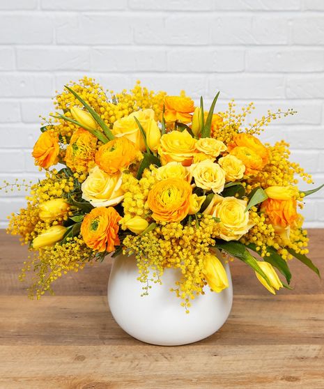 Yellow and orange blooms in a white vessel