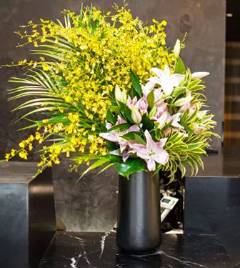 A lush mix of pink, green and gold flowers at the reception desk of a large corporation