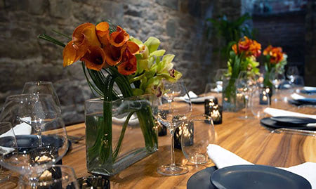 Orange flowers and empty wine glasses at a dinner place setting