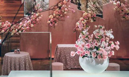 Bright pink and white roses in a vase on a pink patterend tablecloth in a pink room